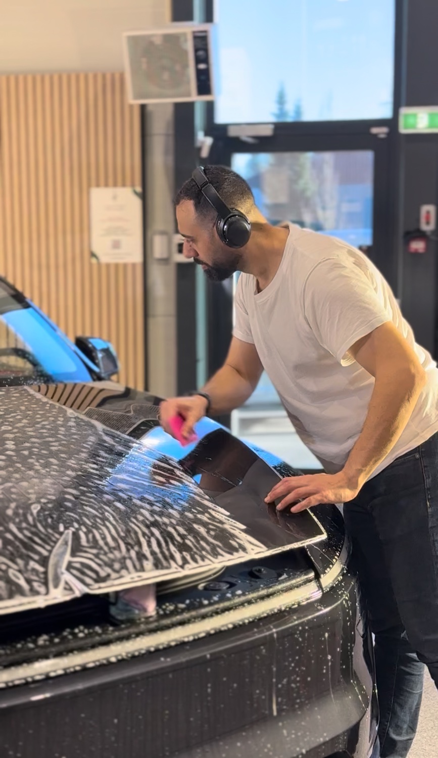 Tekniker monterer PPF-film på fronten av en elbil
